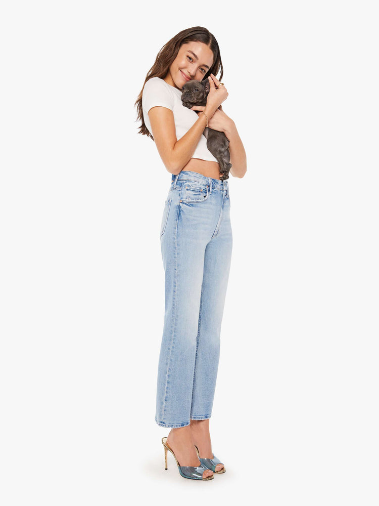 Side angle view of a woman super high-rise jeans with a flared leg, an ankle-length inseam, a slightly dropped crotch and a slouchier fit designed to sit lower on the hips in a light blue wash.