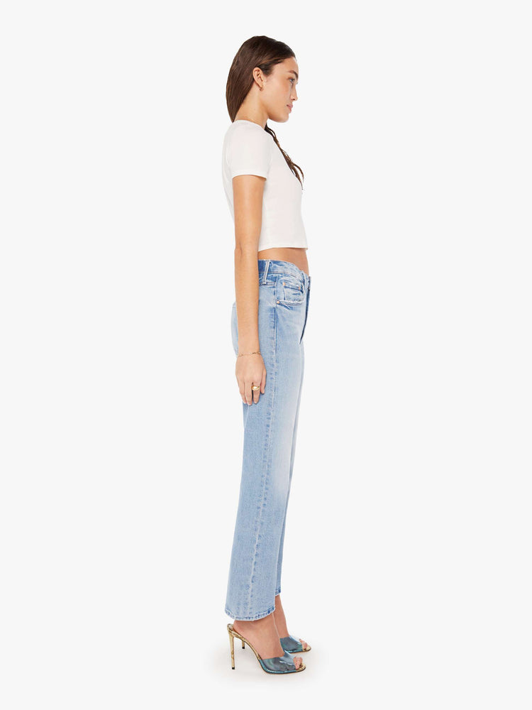 Side view of a woman super high-rise jeans with a flared leg, an ankle-length inseam, a slightly dropped crotch and a slouchier fit designed to sit lower on the hips in a light blue wash.
