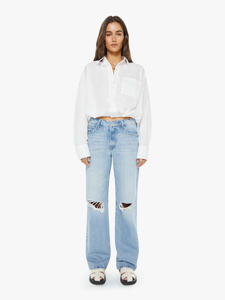 Front view of a woman in a light blue mid-rise jeans with a loose fit, zip fly, wide leg and 32-inch inseam with a clean hem.