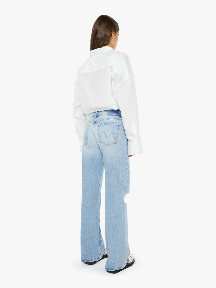 Back view of a woman in a light blue mid-rise jeans with a loose fit, zip fly, wide leg and 32-inch inseam with a clean hem.