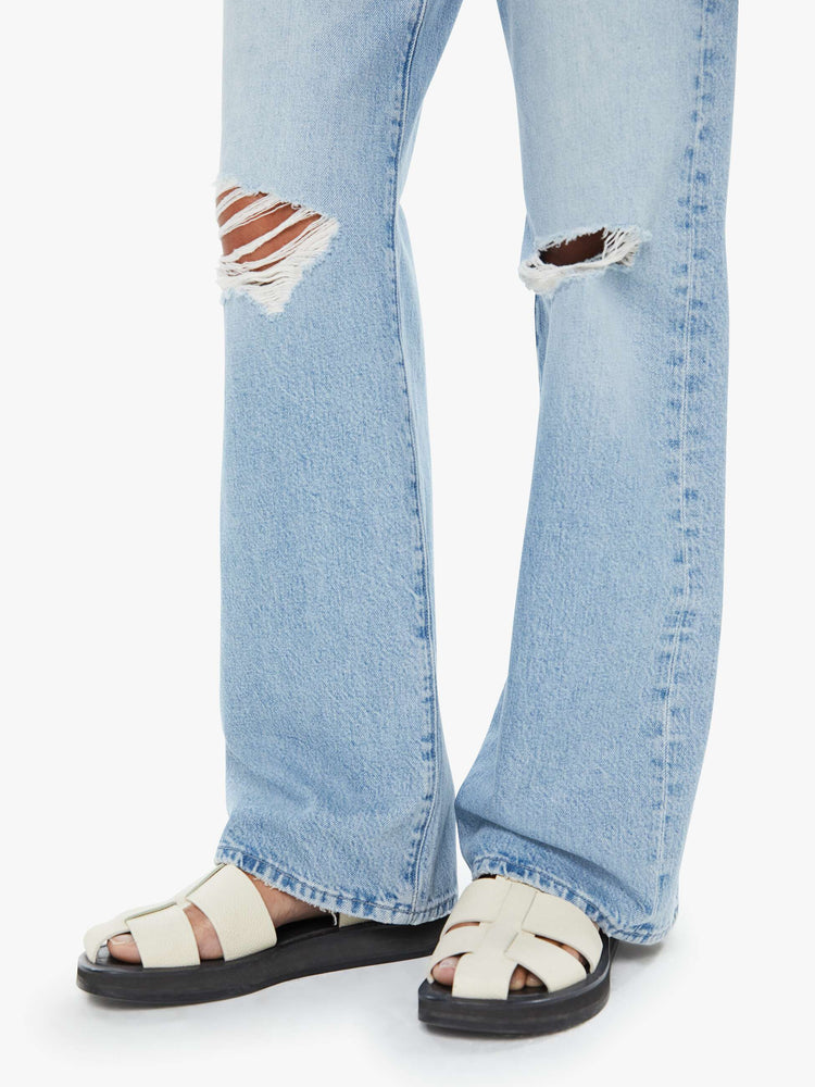 Close up view of a woman in a light blue mid-rise jeans with a loose fit, zip fly, wide leg and 32-inch inseam with a clean hem.