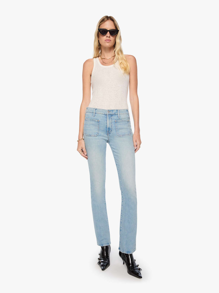 Front view of a woman in a light blue high-waisted bootcut has a zip fly, patch pockets, a 32-inch inseam and a clean hem.