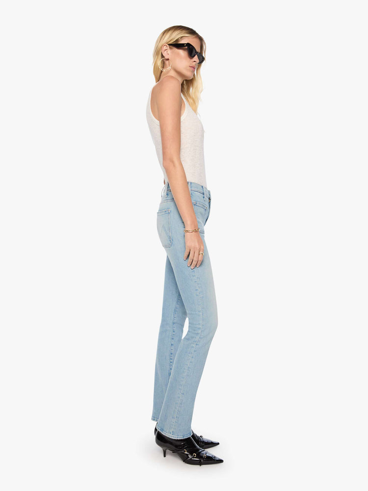 Side view of a woman in a light blue high-waisted bootcut has a zip fly, patch pockets, a 32-inch inseam and a clean hem.