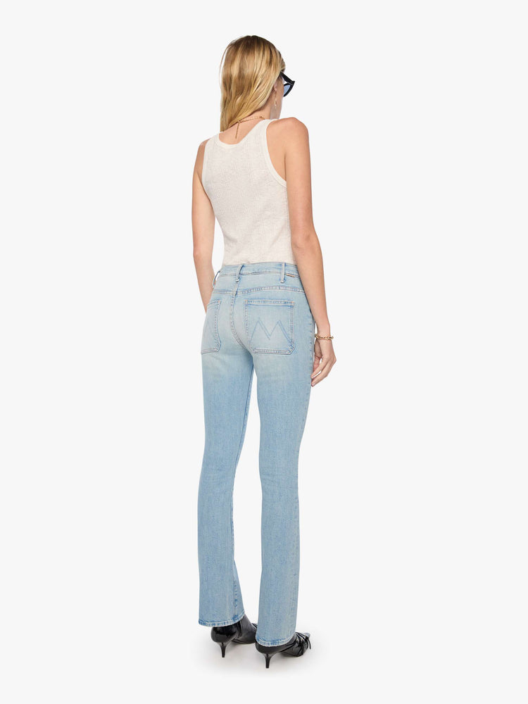 Back view of a woman in a light blue high-waisted bootcut has a zip fly, patch pockets, a 32-inch inseam and a clean hem.
