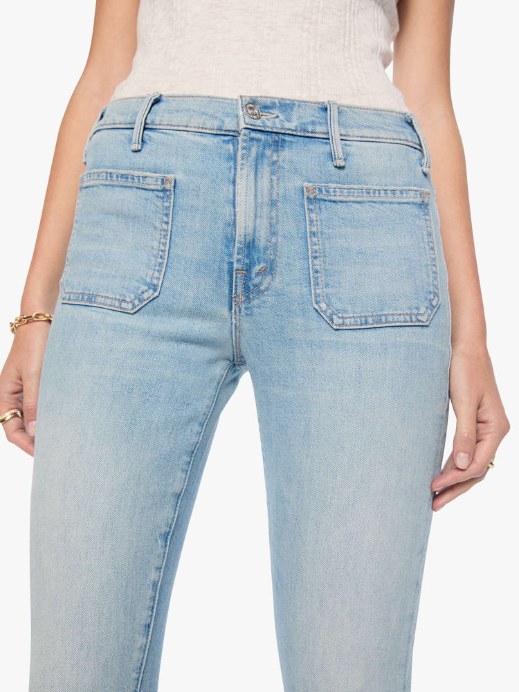 Close up view of a woman in a light blue high-waisted bootcut has a zip fly, patch pockets, a 32-inch inseam and a clean hem.