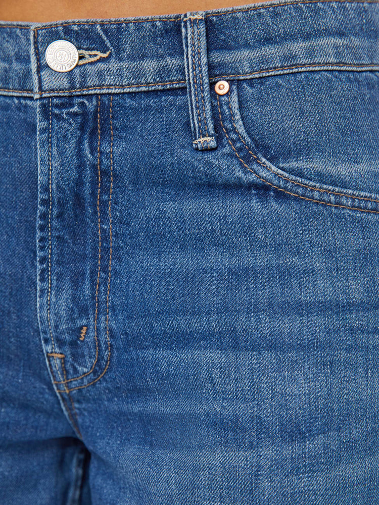 Detailed view of a woman in dark blue slouchy, high-waisted jeans with a loose wide leg and whiskering and fading at the knee. 