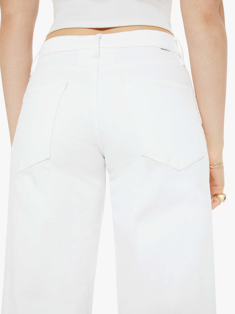 Back close up view of a woman in a white high-waisted jeans with a loose wide leg and a long 32-inch inseam with a clean hem.