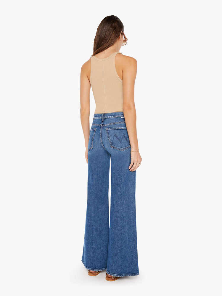 Back view of a medium blue wash jean featuring a high rise and a wide leg flare.