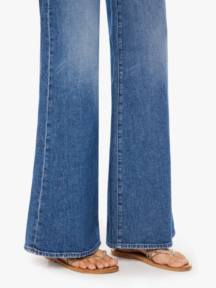 Side close up view of a medium blue wash jean featuring a high rise and a wide leg flare.