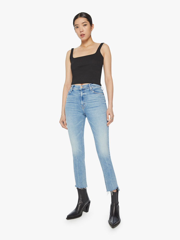 Front view of a woman mid-rise jean has a straight leg with an ankle-length inseam and a frayed step hem in a light blue wash.