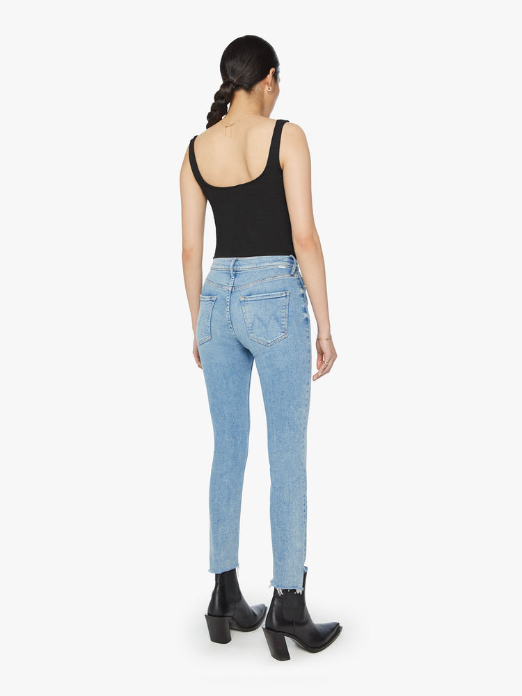 Back view of a woman mid-rise jean has a straight leg with an ankle-length inseam and a frayed step hem in a light blue wash.