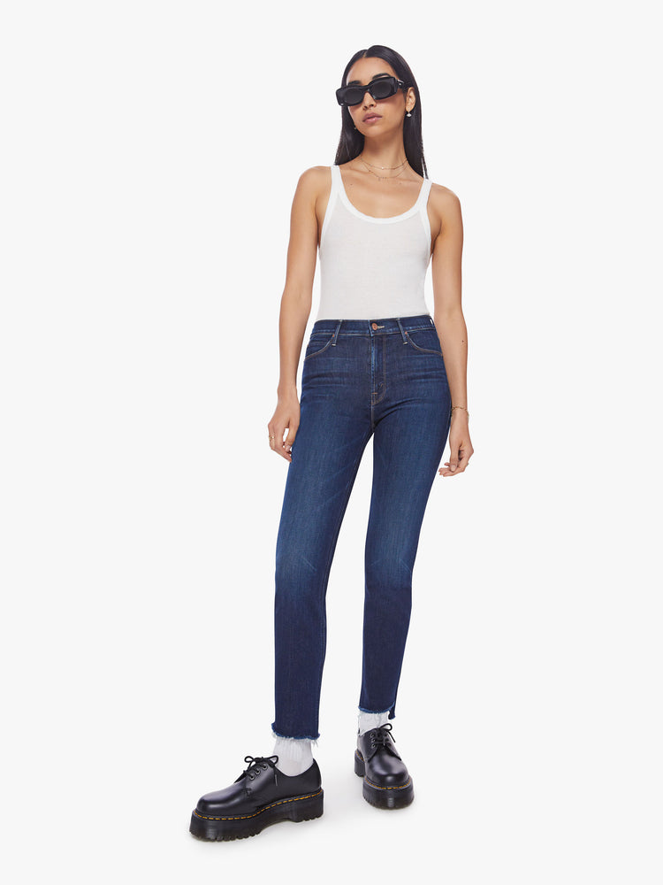 Front view of a dark blue mid-rise jean has a straight leg with an ankle-length inseam and a frayed step hem.
