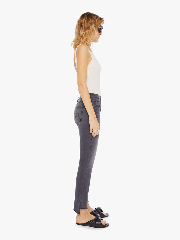 Side view of a women's faded black straight leg jean with a step frayed ankle length hem.