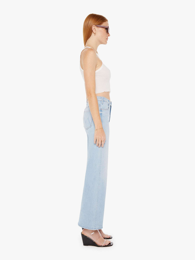 Side view of a womens light blue wash jean featuring a high rise and a flood length flared wide leg.