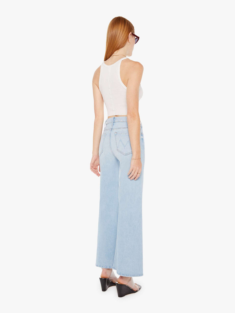 Back view of a womens light blue wash jean featuring a high rise and a flood length flared wide leg.