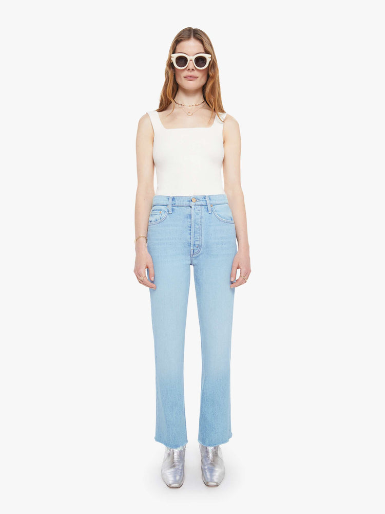 Front view of a woman in a light blue  high-rise flare with a button fly, 28.25-inch inseam and a frayed hem. 