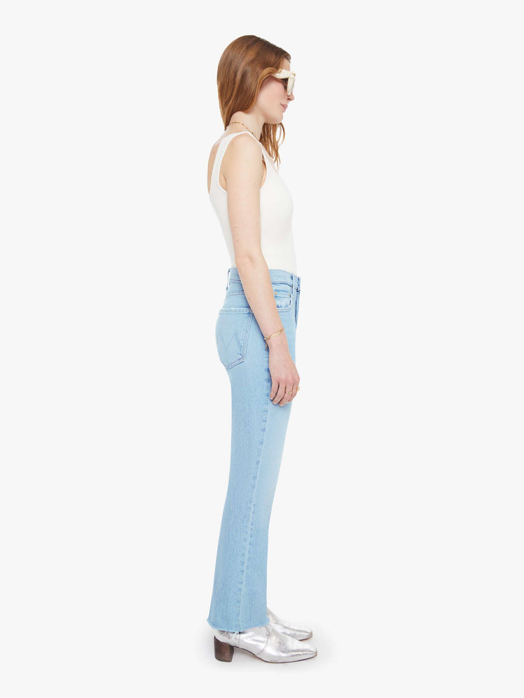 Side view of a woman in a light blue  high-rise flare with a button fly, 28.25-inch inseam and a frayed hem. 