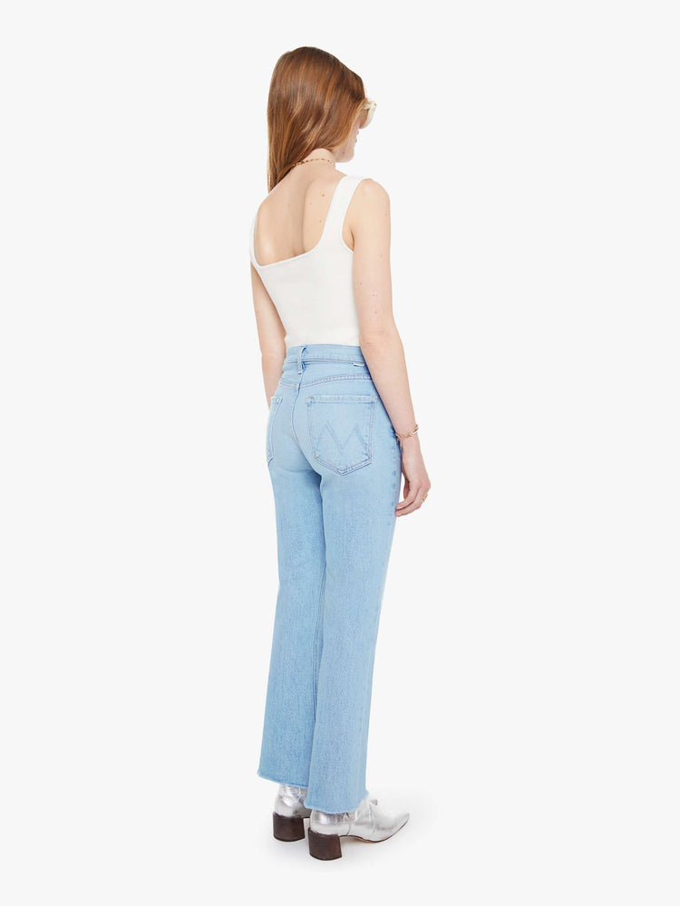 Back view of a woman in a light blue  high-rise flare with a button fly, 28.25-inch inseam and a frayed hem. 