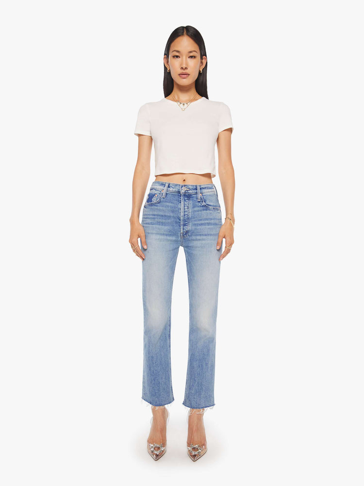 Front view of a womens high rise medium blue wash jean with a flare leg, frayed hem and fading at the knees.