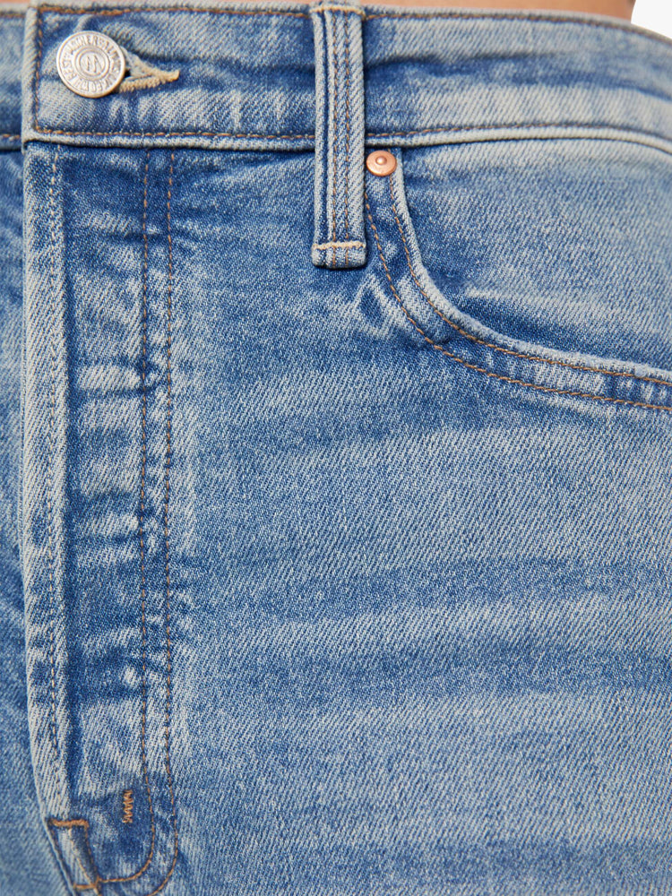Swatch view of a womens high rise medium blue wash jean with a flare leg, frayed hem and fading at the knees.