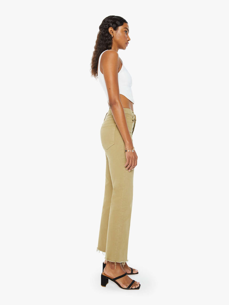 Side view of a woman in warm khaki high-rise flare with a button fly and a frayed hem.