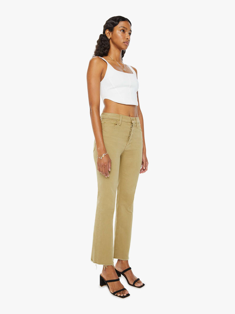 Angled view of a woman in warm khaki high-rise flare with a button fly and a frayed hem.