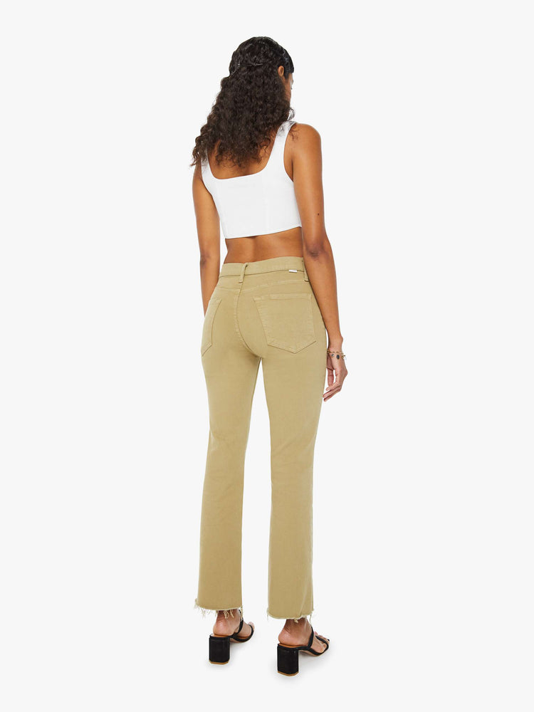Back view of a woman in warm khaki high-rise flare with a button fly and a frayed hem.