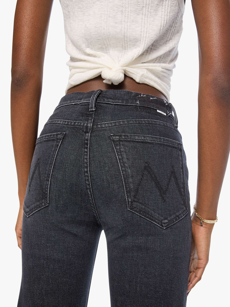 Close up view of a woman in a washed black high-rise jeans with a straight leg, zip fly and a 32-inch inseam with a clean hem.