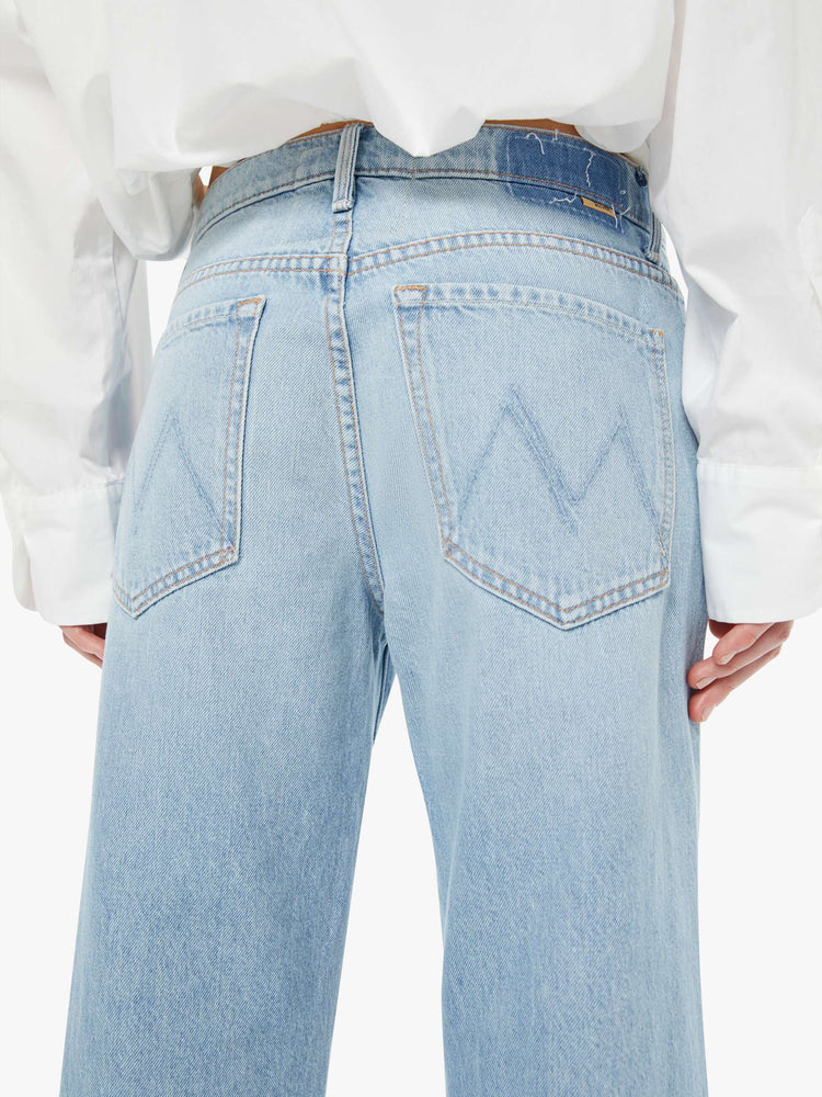Back close up view of a woman in a light blue mid-rise jeans with a wide straight leg, zip fly and frayed ankle-length inseam.