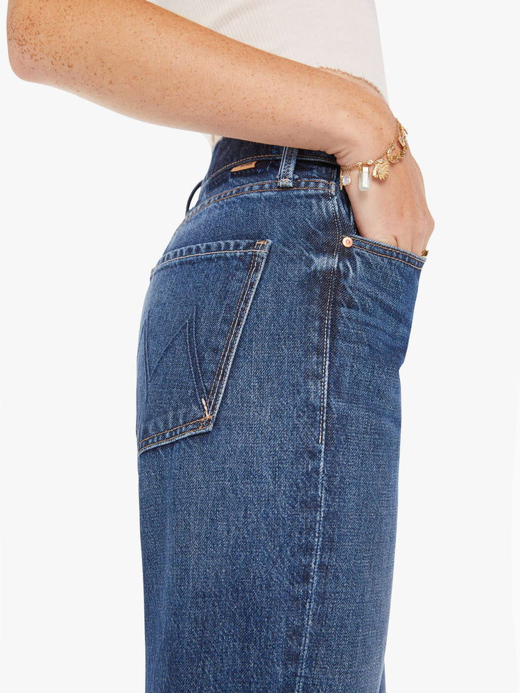 Side close up view of a pair of dark blue jeans featuring a wide bootcut and a slouchy relaxed fit.