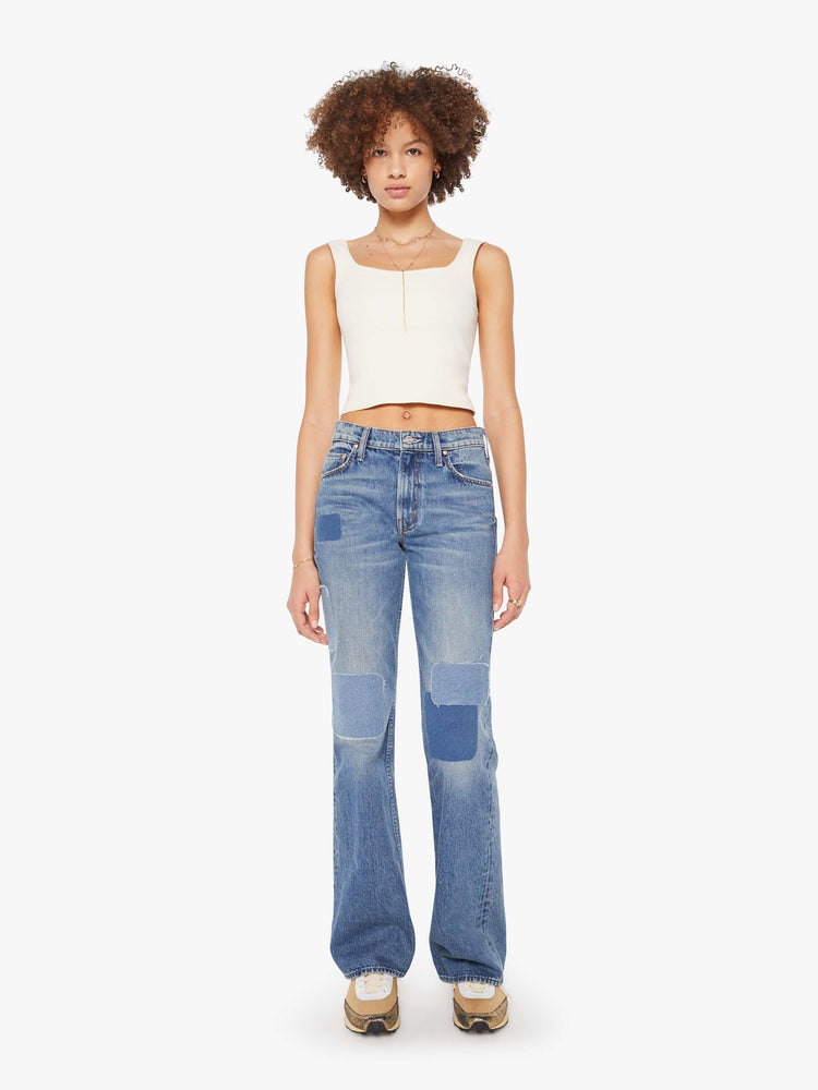 Front view of a woman in high-rise bootcut with a looser leg and a long 34-inch inseam with a clean hem in a mid blue wash.