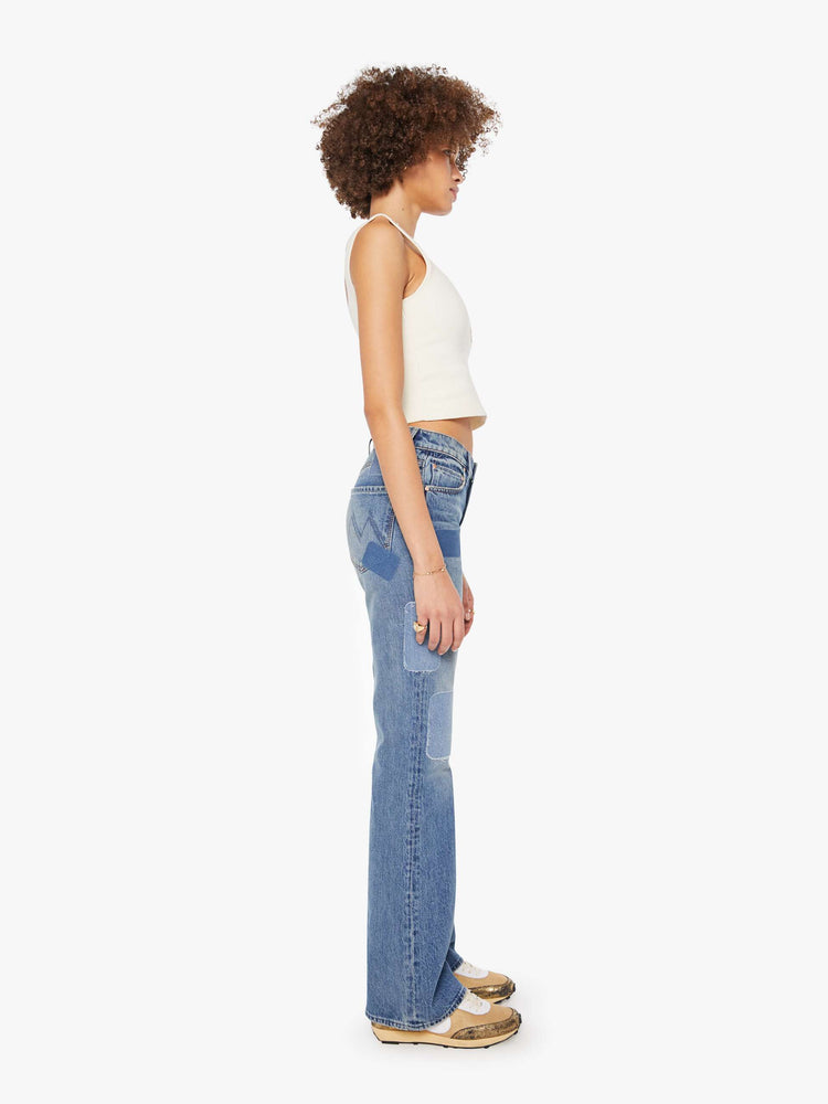 Side view of a woman in high-rise bootcut with a looser leg and a long 34-inch inseam with a clean hem in a mid blue wash.