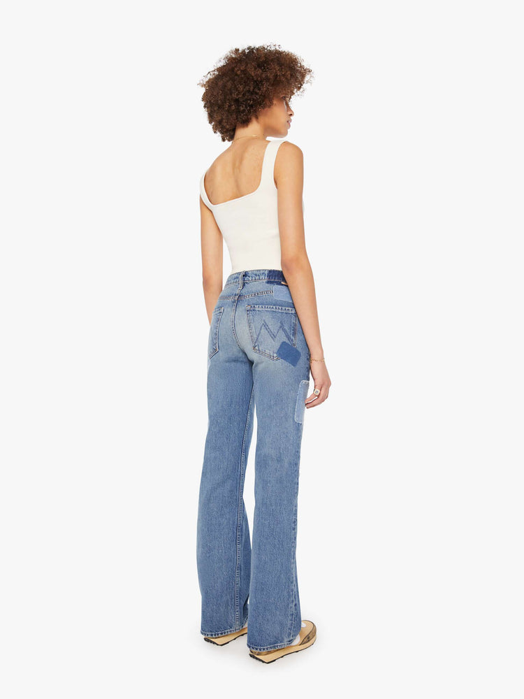 Back view of a woman in high-rise bootcut with a looser leg and a long 34-inch inseam with a clean hem in a mid blue wash.