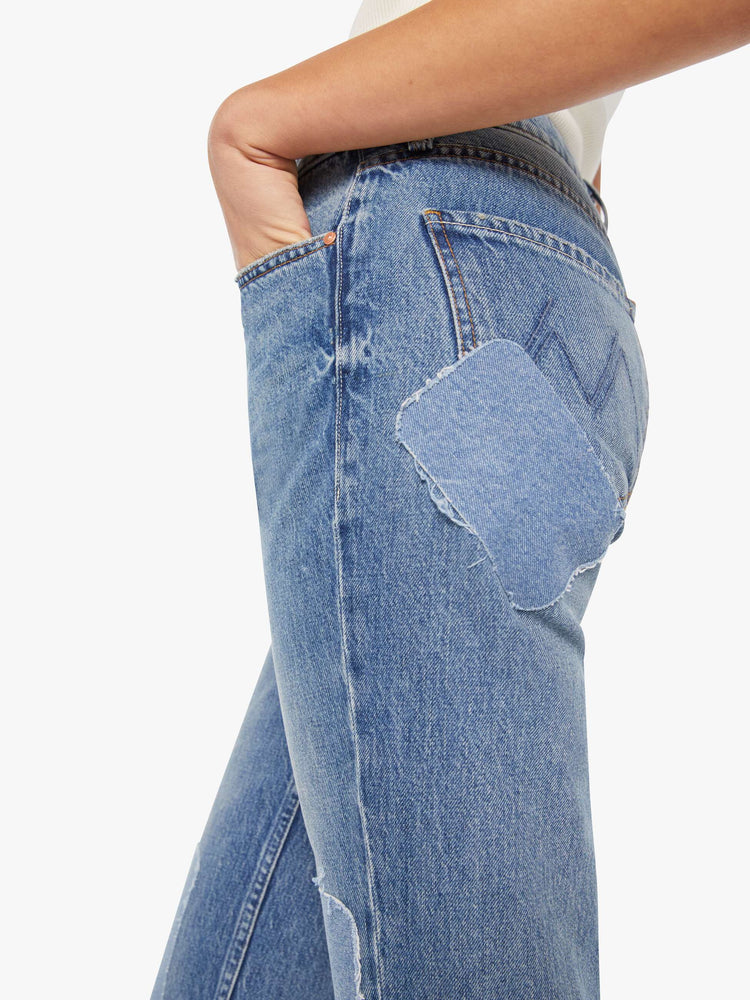 Close up view of a woman in high-rise bootcut with a looser leg and a long 34-inch inseam with a clean hem in a mid blue wash.