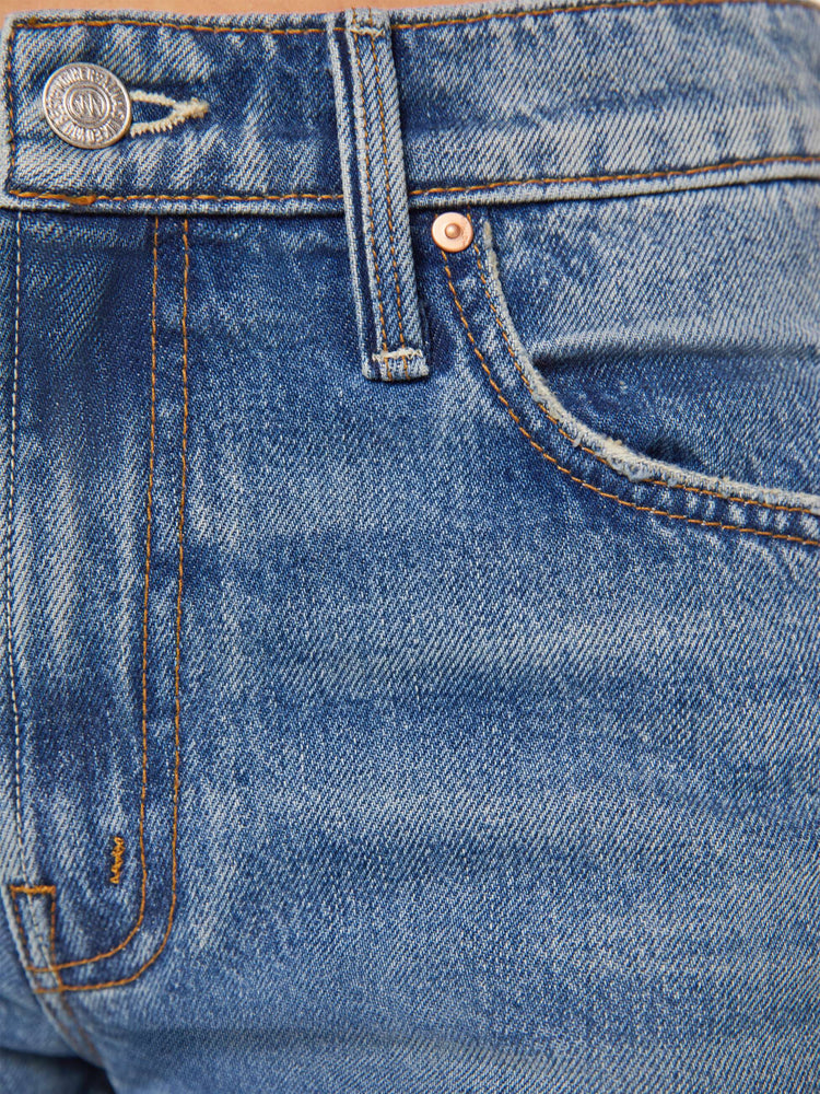 Swatch view of a woman in high-rise bootcut with a looser leg and a long 34-inch inseam with a clean hem in a mid blue wash.