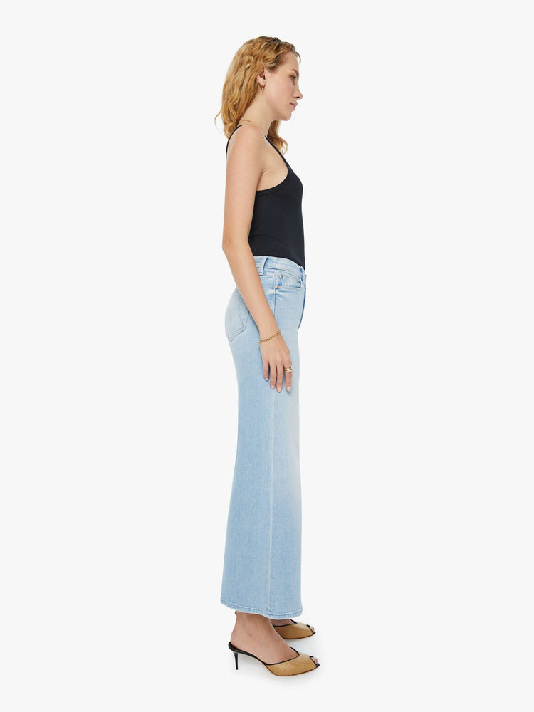Side view of a woman in light blue high-rise jeans with a wide leg and a clean hem.
