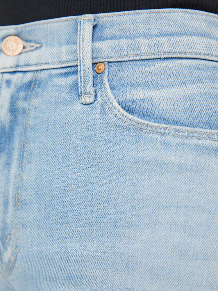 Detailed view of a woman in light blue high-rise jeans with a wide leg and a clean hem.