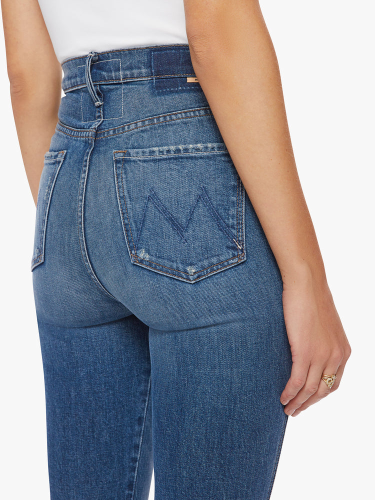 Close up waist view of a woman high-rise slim-straight leg has a long 34-inch inseam with a clean hem in a dark blue wash.