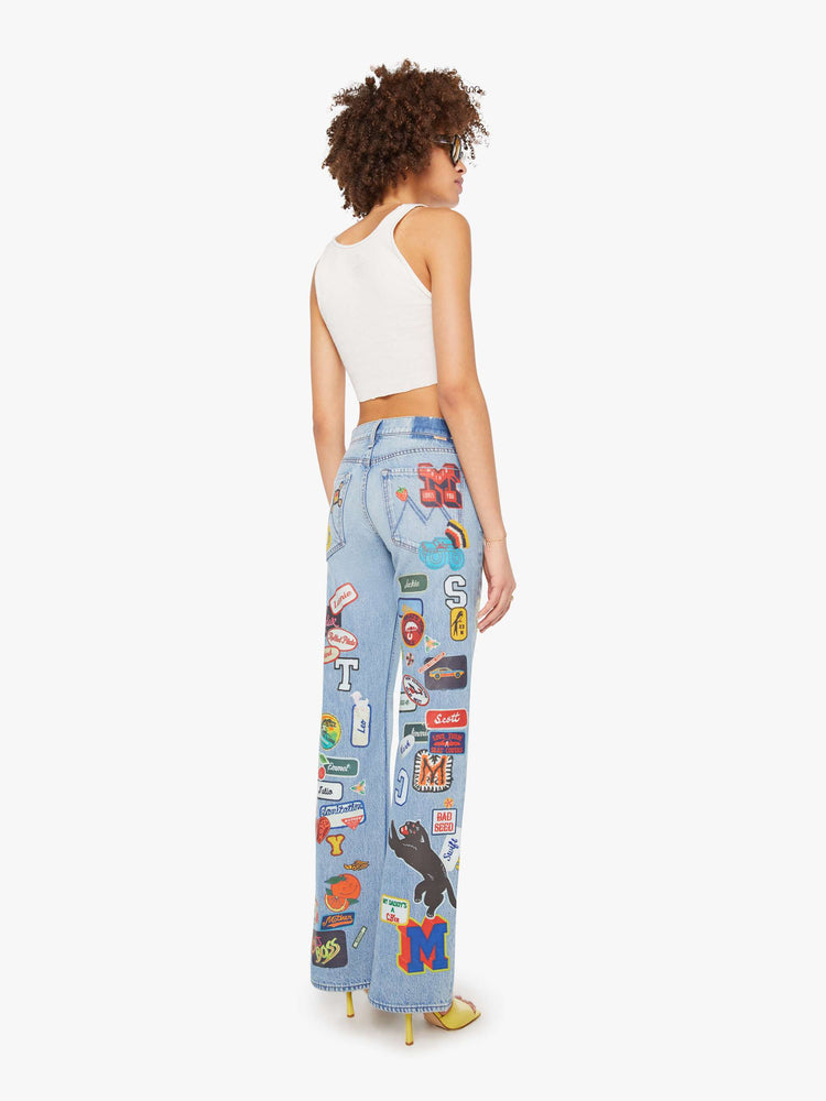 Back view of a woman in a light blue and colorful vinyl patches thoughout high-rise bootcut jean with a zip fly, looser leg and a 32-inch inseam with a clean hem. 