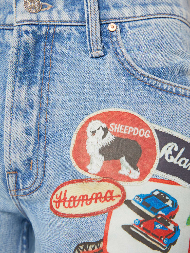 Swatch view of a woman in a light blue and colorful vinyl patches thoughout high-rise bootcut jean with a zip fly, looser leg and a 32-inch inseam with a clean hem. 