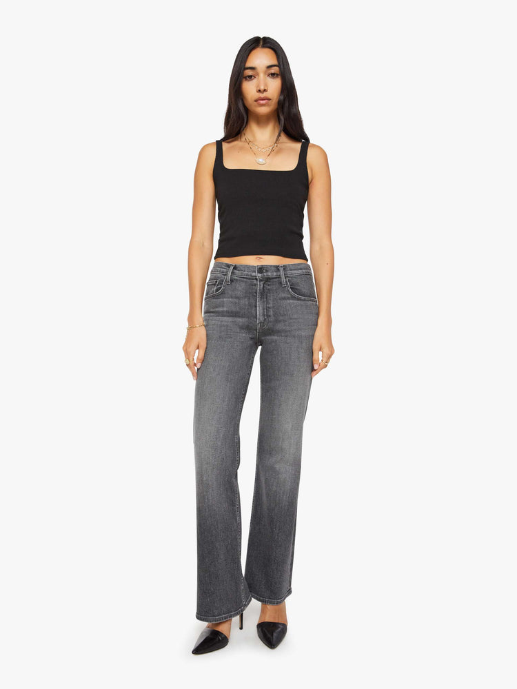 Front view of a woman in a dark grey mid-rise bootcut with a zip fly, looser leg and a long 32-inch inseam with a clean hem.