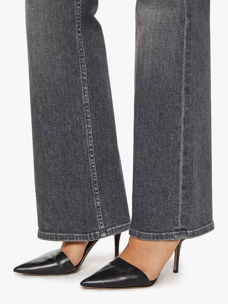 Hem view of a woman in a dark grey mid-rise bootcut with a zip fly, looser leg and a long 32-inch inseam with a clean hem.