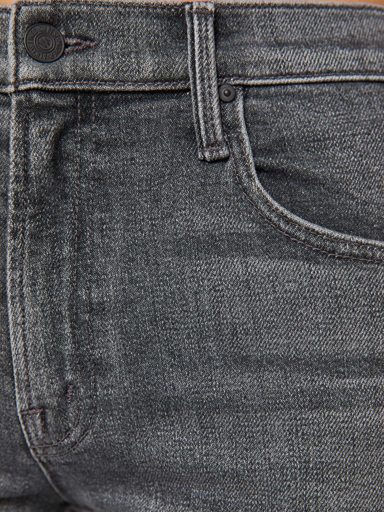 Swatch view of a woman in a dark grey mid-rise bootcut with a zip fly, looser leg and a long 32-inch inseam with a clean hem.