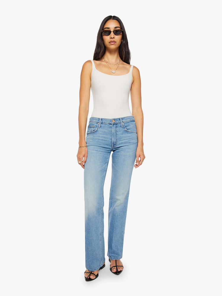 Front view of a woman in a light blue mid-rise bootcut with a zip fly, looser leg and a long 32-inch inseam with a clean hem.