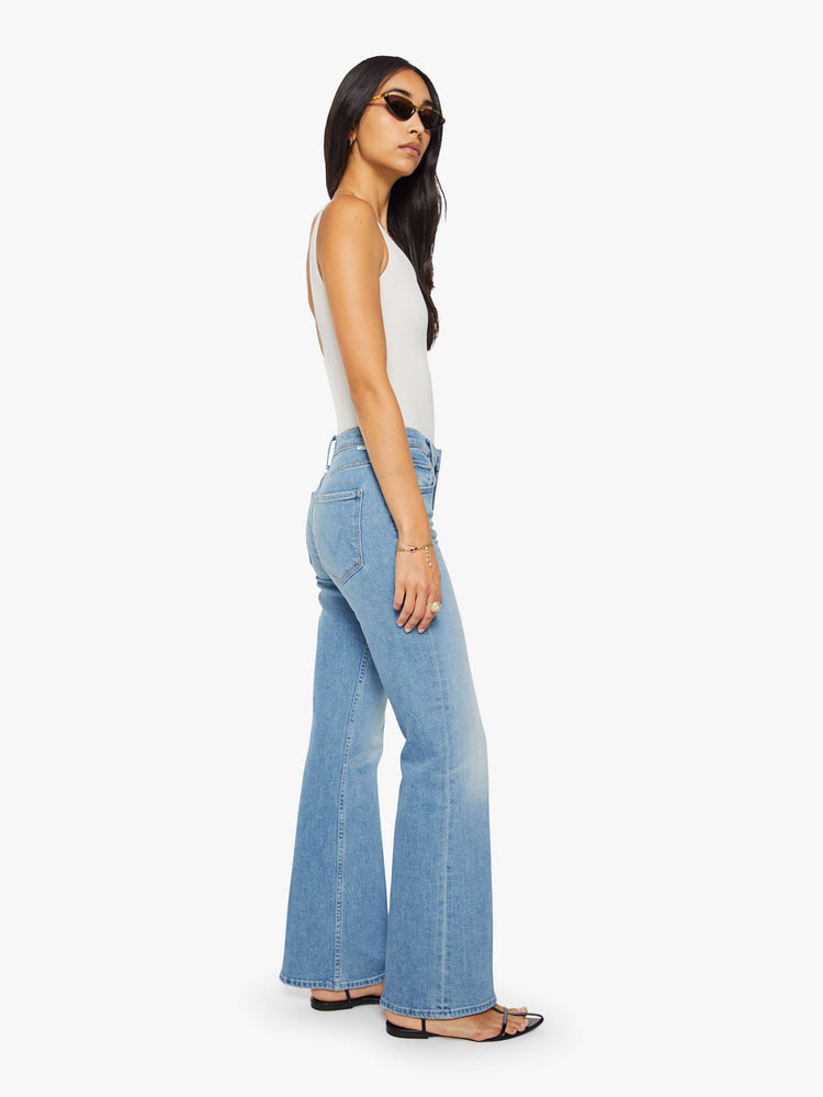 Side view of a woman in a light blue mid-rise bootcut with a zip fly, looser leg and a long 32-inch inseam with a clean hem.