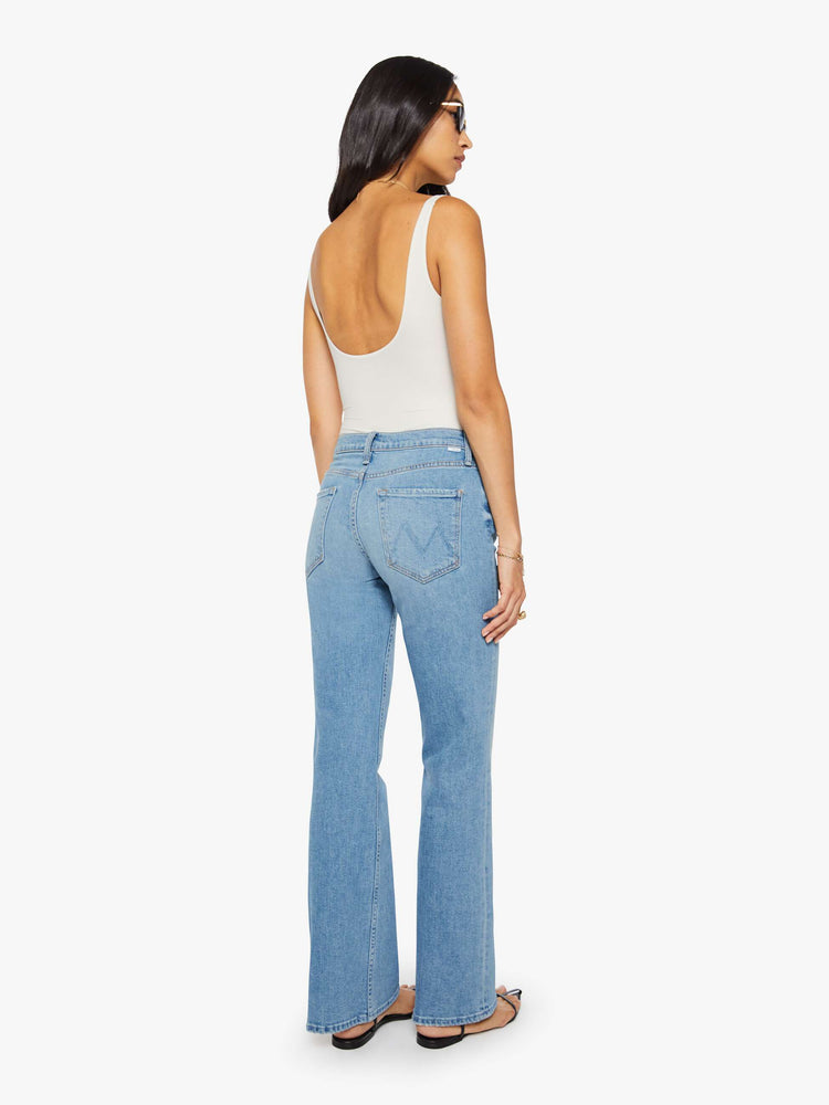 Back view of a woman in a light blue mid-rise bootcut with a zip fly, looser leg and a long 32-inch inseam with a clean hem.