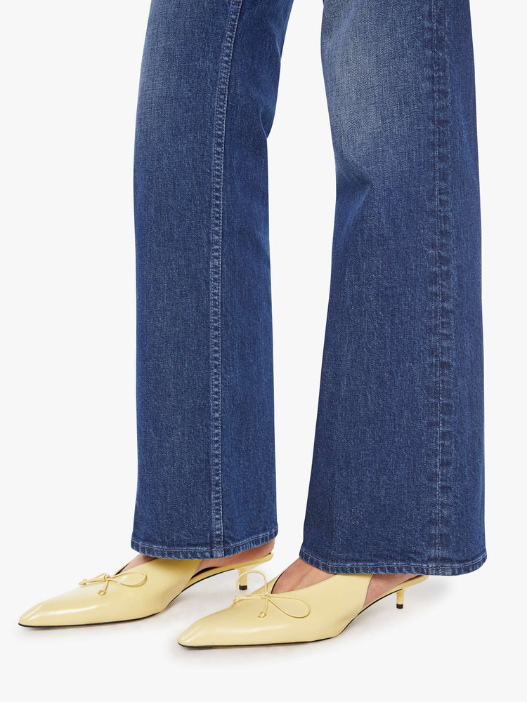 Hem view of a woman in a dark blue high-rise bootcut jean with a zip fly, looser leg and a long 32-inch inseam with a clean hem.