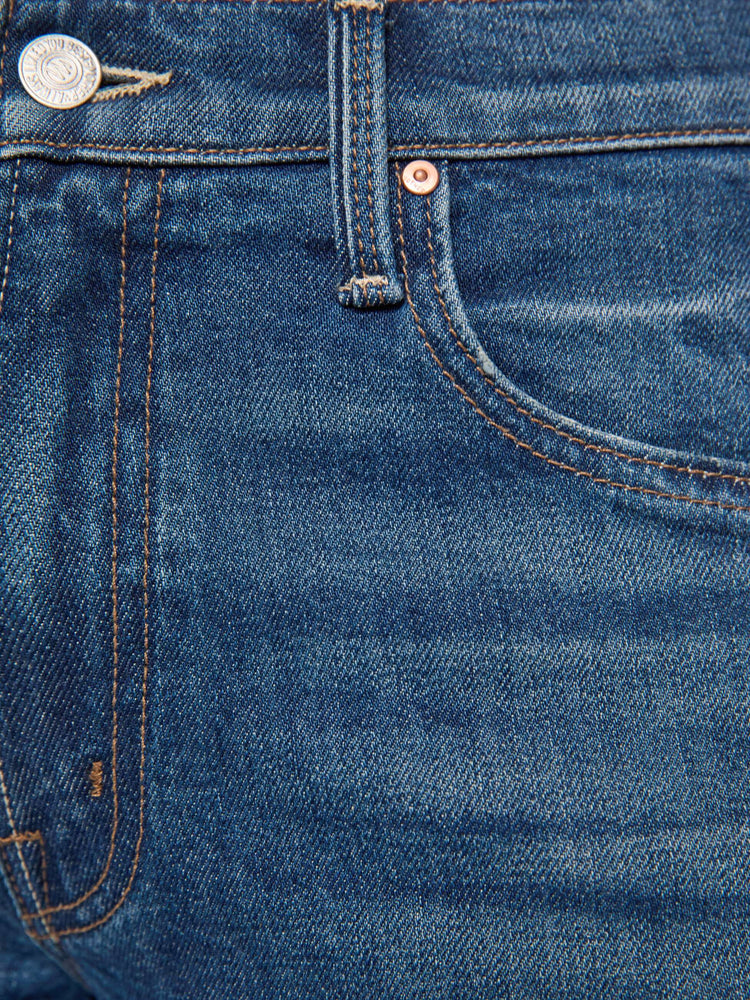 Swatch view of a woman in mid-blue mid-rise bootcut with a zip fly, looser leg and a long 32-inch inseam with a clean hem.