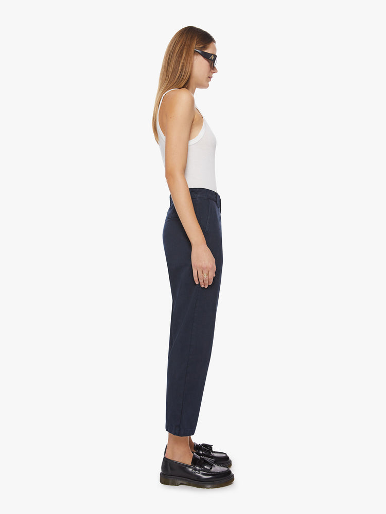 Side view of a woman navy trouser borrowed from MOTHER's men's collection with a high rise, tapered leg, slash pockets and an ankle-length inseam.