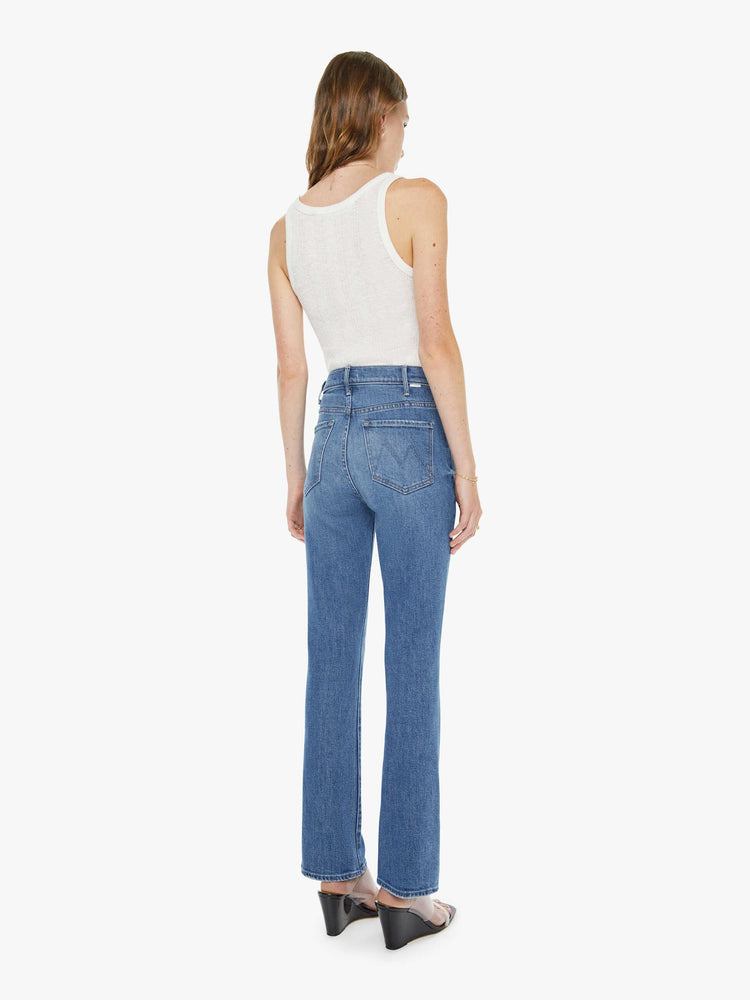 Back view of a woman in a mid blue high-rise flare has a zip fly, 28.25-inch inseam and a clean hem.